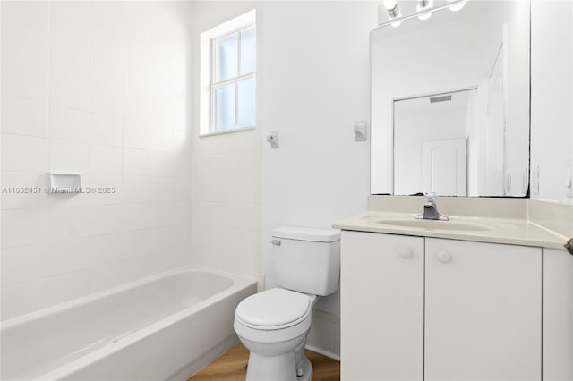 full bathroom featuring hardwood / wood-style flooring, vanity, tiled shower / bath combo, and toilet