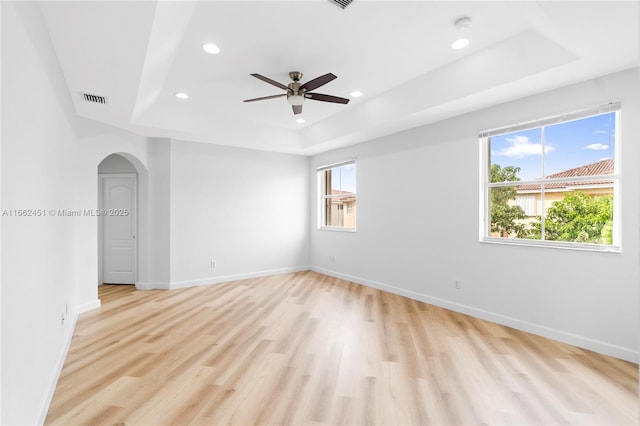 spare room featuring ceiling fan, a tray ceiling, and light wood-type flooring