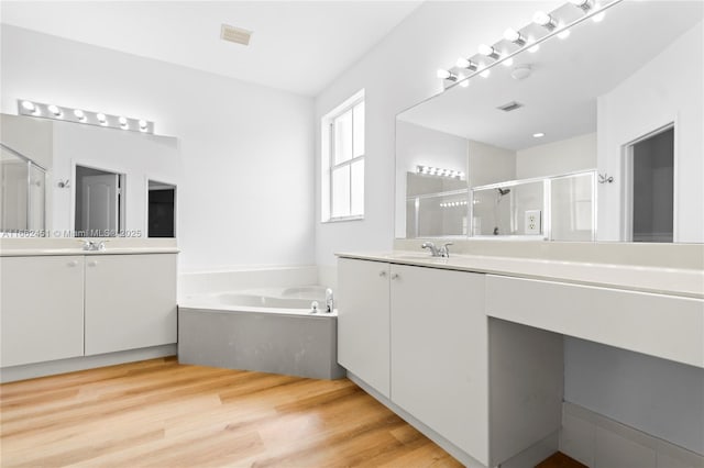 bathroom featuring wood-type flooring, plus walk in shower, and vanity