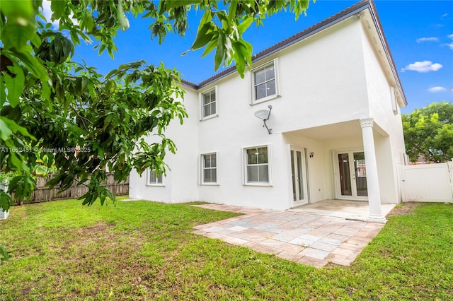 back of property with french doors, a patio, and a lawn