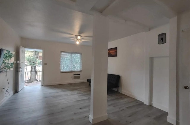 unfurnished living room featuring wood finished floors, an AC wall unit, baseboards, and ceiling fan