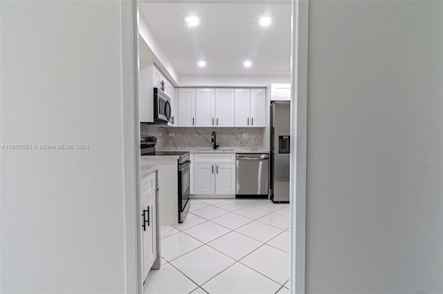 kitchen with white cabinets, light tile patterned floors, sink, tasteful backsplash, and stainless steel appliances