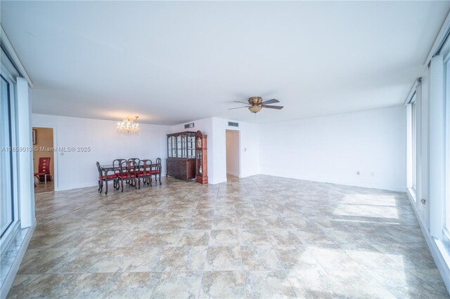 unfurnished living room featuring ceiling fan with notable chandelier