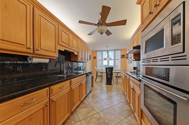 kitchen with stainless steel appliances, dark stone counters, tasteful backsplash, sink, and light tile patterned floors