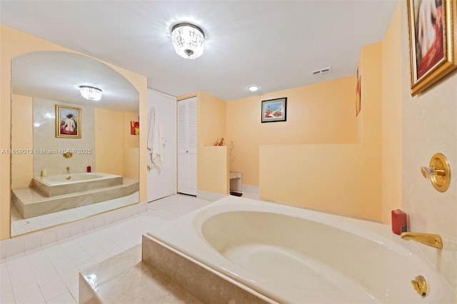 bathroom with tile patterned floors and a relaxing tiled tub