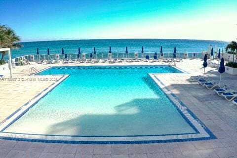 view of pool with a water view and a patio area