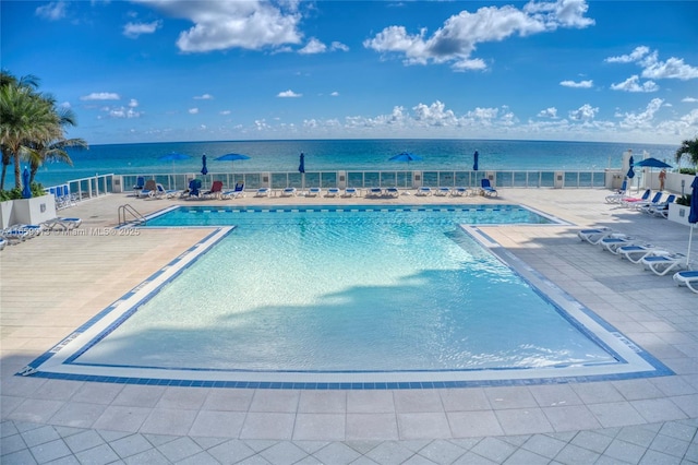 view of pool featuring a water view and a patio