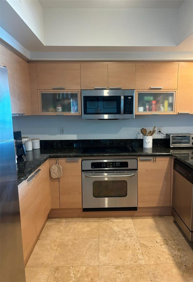 kitchen with dark stone counters and stainless steel appliances