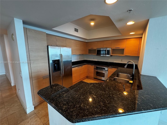 14951 Royal Oaks Ln Unit 1504, North Miami, FL 33181 - kitchen featuring appliances with stainless steel finishes, a sink, a peninsula, a raised ceiling, and dark stone counters