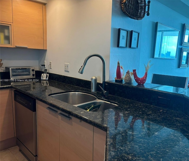 kitchen with dark stone counters, sink, light tile patterned flooring, and stainless steel dishwasher