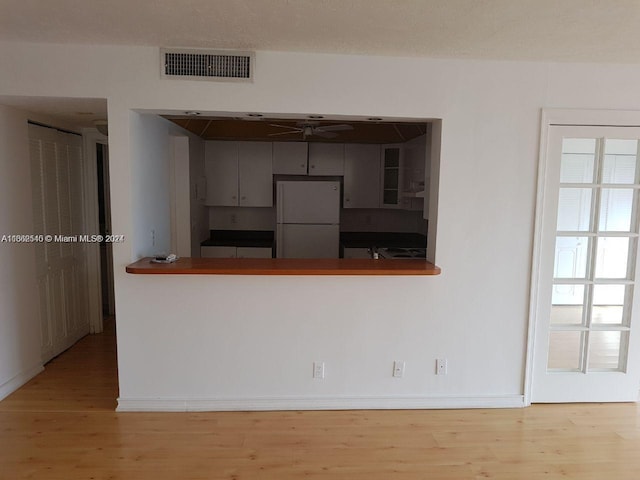 kitchen with kitchen peninsula, ceiling fan, light hardwood / wood-style flooring, and white refrigerator