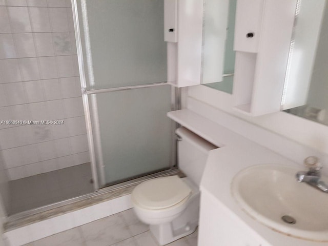 bathroom featuring vanity, toilet, an enclosed shower, and tile patterned floors