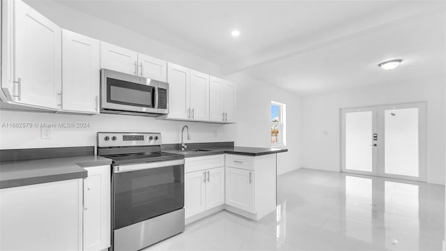 kitchen with stainless steel appliances, white cabinetry, beamed ceiling, and sink