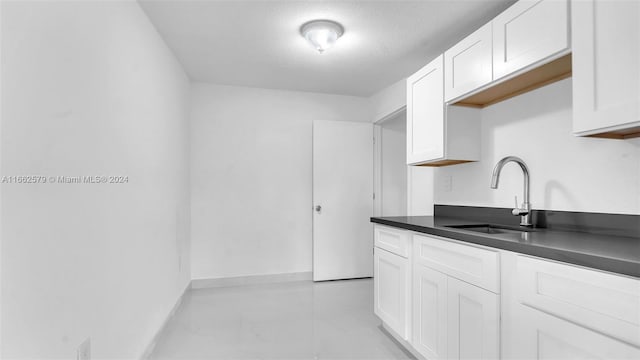 kitchen featuring a textured ceiling, white cabinetry, and sink