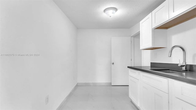 kitchen featuring white cabinets, a textured ceiling, and sink