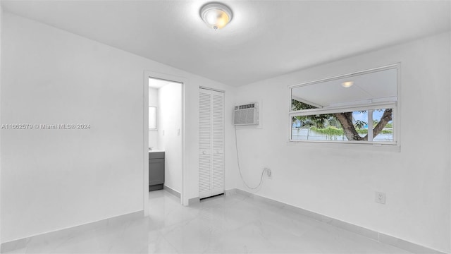 unfurnished bedroom featuring vaulted ceiling, a closet, ensuite bathroom, and a wall mounted AC