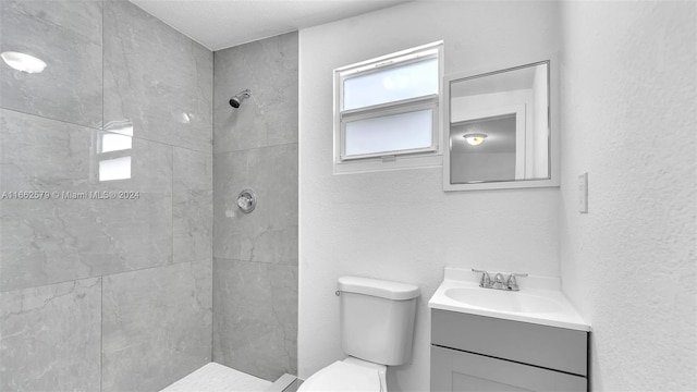 bathroom with toilet, vanity, and tiled shower