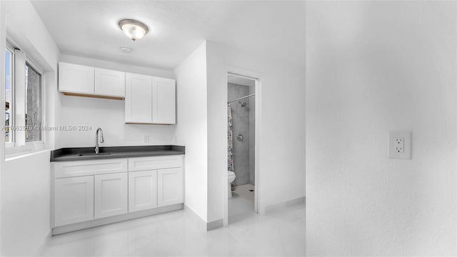 kitchen featuring a wealth of natural light, sink, and white cabinetry