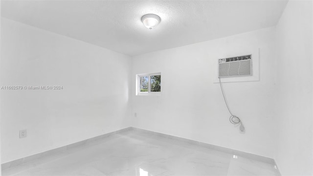 empty room featuring an AC wall unit and a textured ceiling