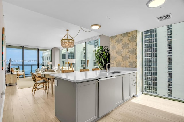 kitchen featuring expansive windows, a water view, sink, and pendant lighting