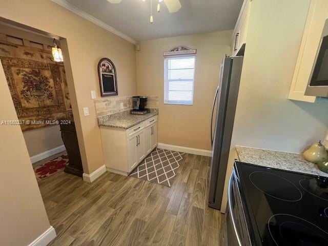 kitchen with ceiling fan, white cabinets, wood-type flooring, appliances with stainless steel finishes, and light stone countertops