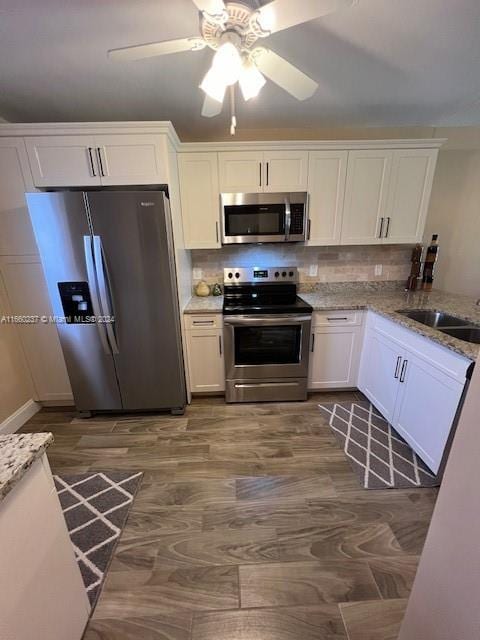 kitchen with appliances with stainless steel finishes, white cabinetry, backsplash, ceiling fan, and sink