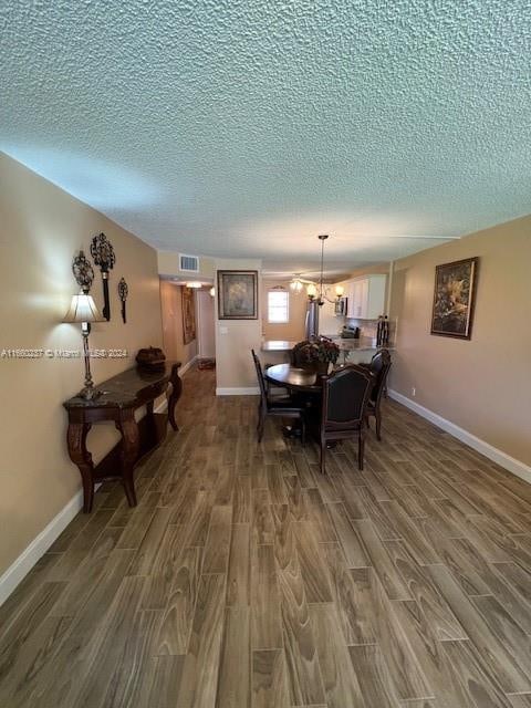 dining area with a notable chandelier, a textured ceiling, and hardwood / wood-style flooring