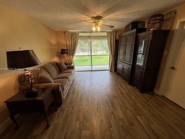 living room with ceiling fan, a textured ceiling, and dark hardwood / wood-style flooring