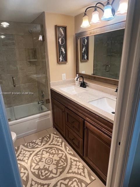 full bathroom with tile patterned flooring, shower / bath combination with glass door, vanity, and toilet