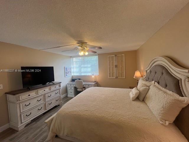 bedroom with ceiling fan, a textured ceiling, and dark hardwood / wood-style flooring