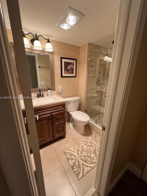 bathroom with vanity, tile patterned flooring, toilet, and an enclosed shower