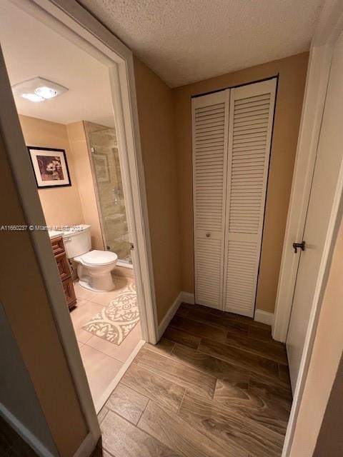 bathroom with vanity, a textured ceiling, hardwood / wood-style flooring, walk in shower, and toilet