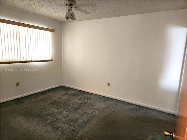 unfurnished room featuring dark carpet, a textured ceiling, and ceiling fan