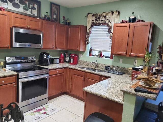 kitchen featuring light stone counters, appliances with stainless steel finishes, light tile patterned floors, and sink