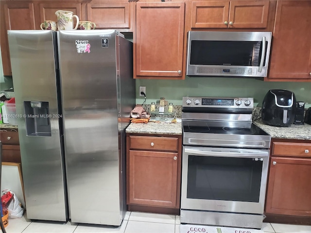 kitchen featuring appliances with stainless steel finishes, light stone countertops, and light tile patterned floors