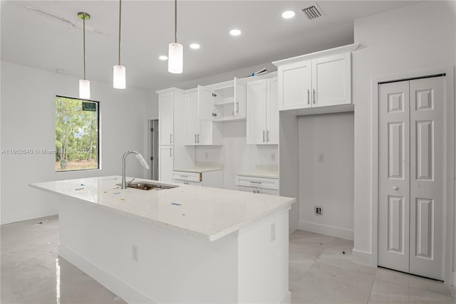 kitchen with white cabinets, a center island with sink, hanging light fixtures, and sink