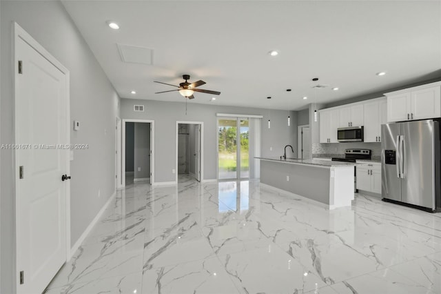 kitchen featuring white cabinetry, light stone countertops, stainless steel appliances, ceiling fan, and a center island with sink