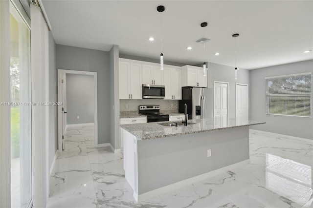 kitchen with white cabinets, hanging light fixtures, sink, a kitchen island with sink, and appliances with stainless steel finishes