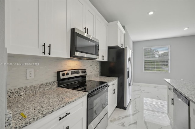 kitchen featuring light stone counters, appliances with stainless steel finishes, backsplash, and white cabinetry