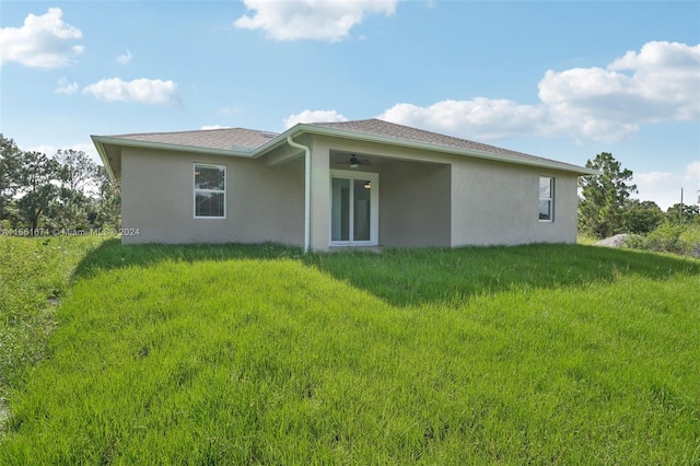 back of house with ceiling fan and a yard