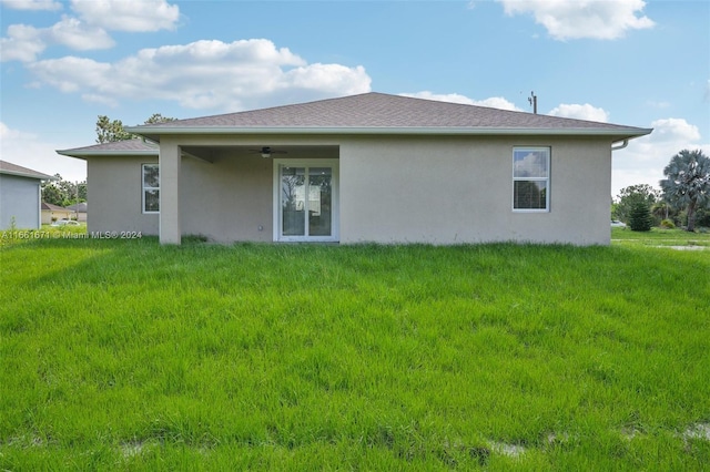 back of property featuring ceiling fan and a lawn