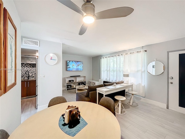 dining space featuring baseboards, visible vents, light wood-style floors, and ceiling fan