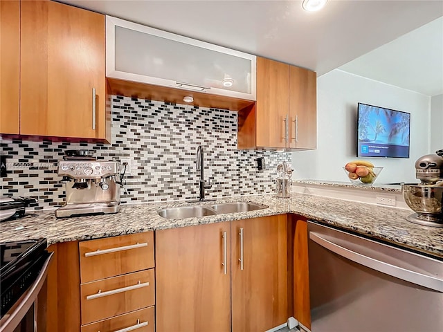 kitchen with appliances with stainless steel finishes, sink, light stone counters, and tasteful backsplash