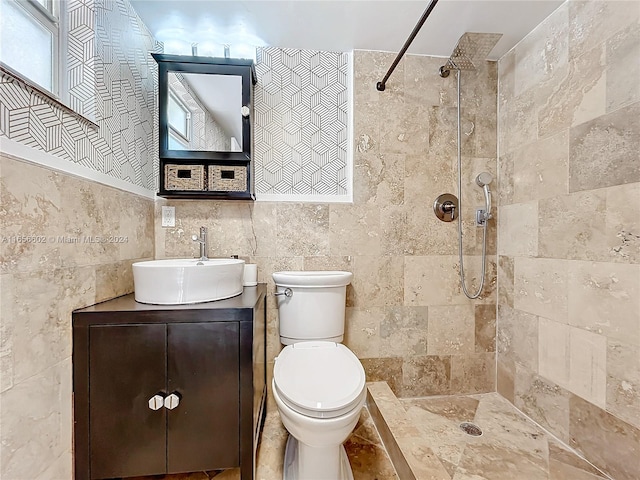 bathroom featuring vanity, toilet, tile walls, and a tile shower