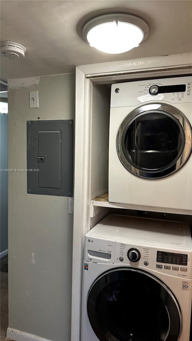 clothes washing area with stacked washing maching and dryer and electric panel