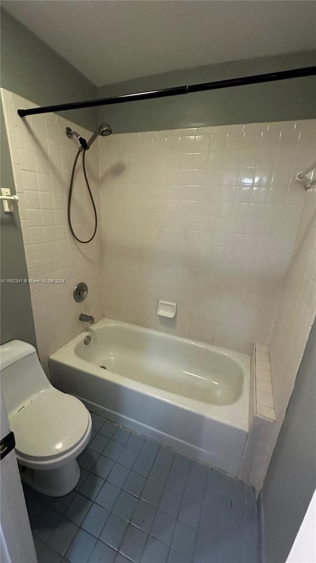 bathroom with toilet, tiled shower / bath, and tile patterned flooring