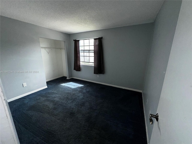 spare room with dark carpet and a textured ceiling