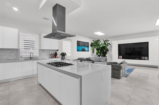 kitchen featuring stainless steel gas cooktop, white cabinetry, island exhaust hood, and a center island