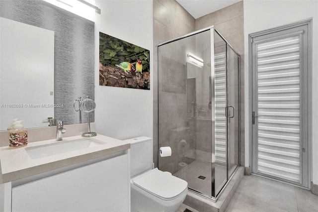 bathroom featuring vanity, a shower with shower door, toilet, and tile patterned floors