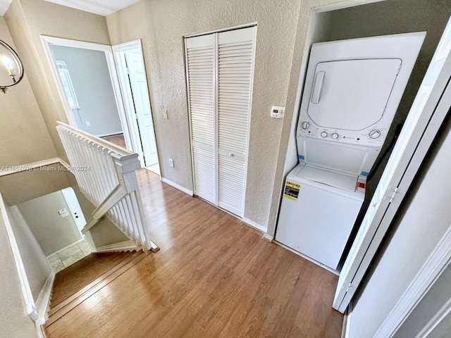 laundry area with wood-type flooring and stacked washer and clothes dryer